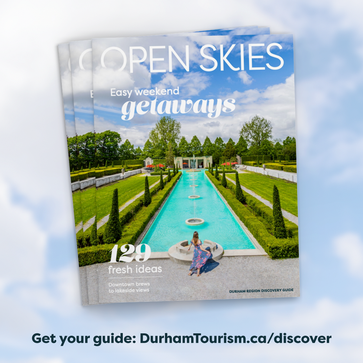 multiple copies of the Open Skies destination guide on a cloudy, blue sky backdrop with text: get your guide: DurhamTourism.ca/discover