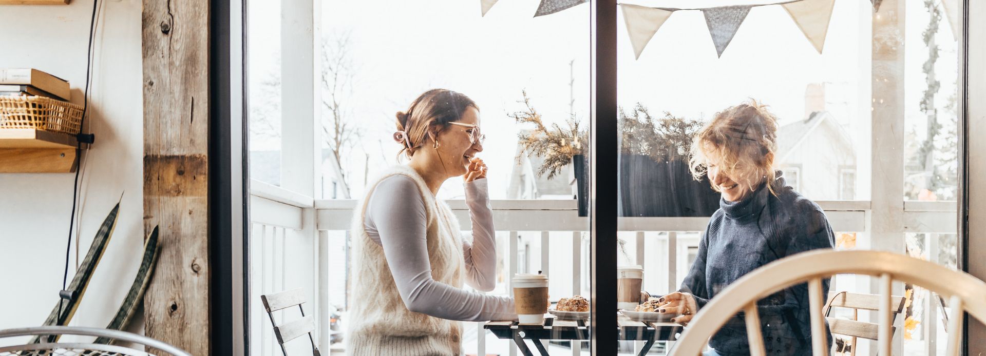 Two women smiling and enjoying coffee at Bean & Basket cafe in Ajax, Ontario, Canada.