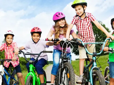 Kids smiling on bicycles wearing their helmets properly. 