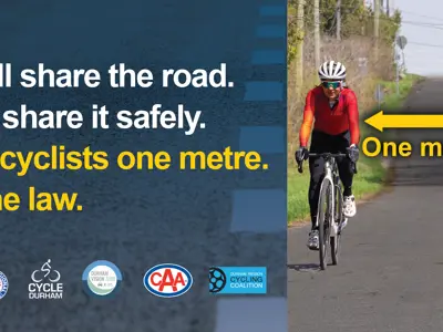 Road safety graphic showing a person riding a bicycle on a rural road with a car passing nearby. Text reads, “We all share the road. Let’s share it safely. Give cyclists one metre. It’s the law,” alongside a yellow arrow indicating a one-metre passing distance, with Durham Region and partner logos at the bottom.