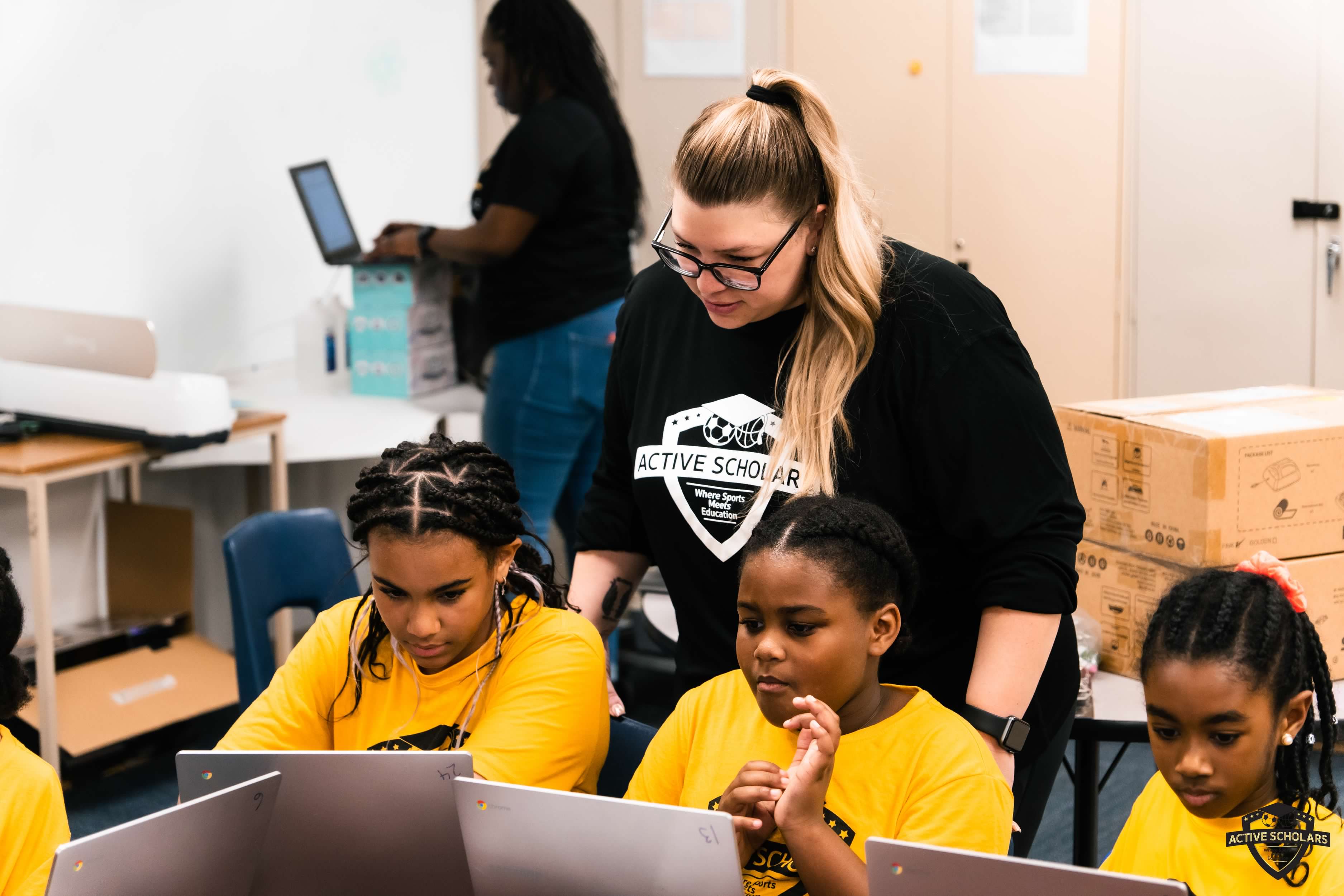 Woman teaching three children on computers