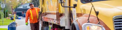 Worker-smiling-on-back-of-waste-truck-banner.jpg
