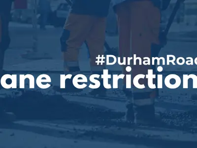 A pylon on a road with a light blue filter over it and white text reading #DurhamRoads Lane restrictions