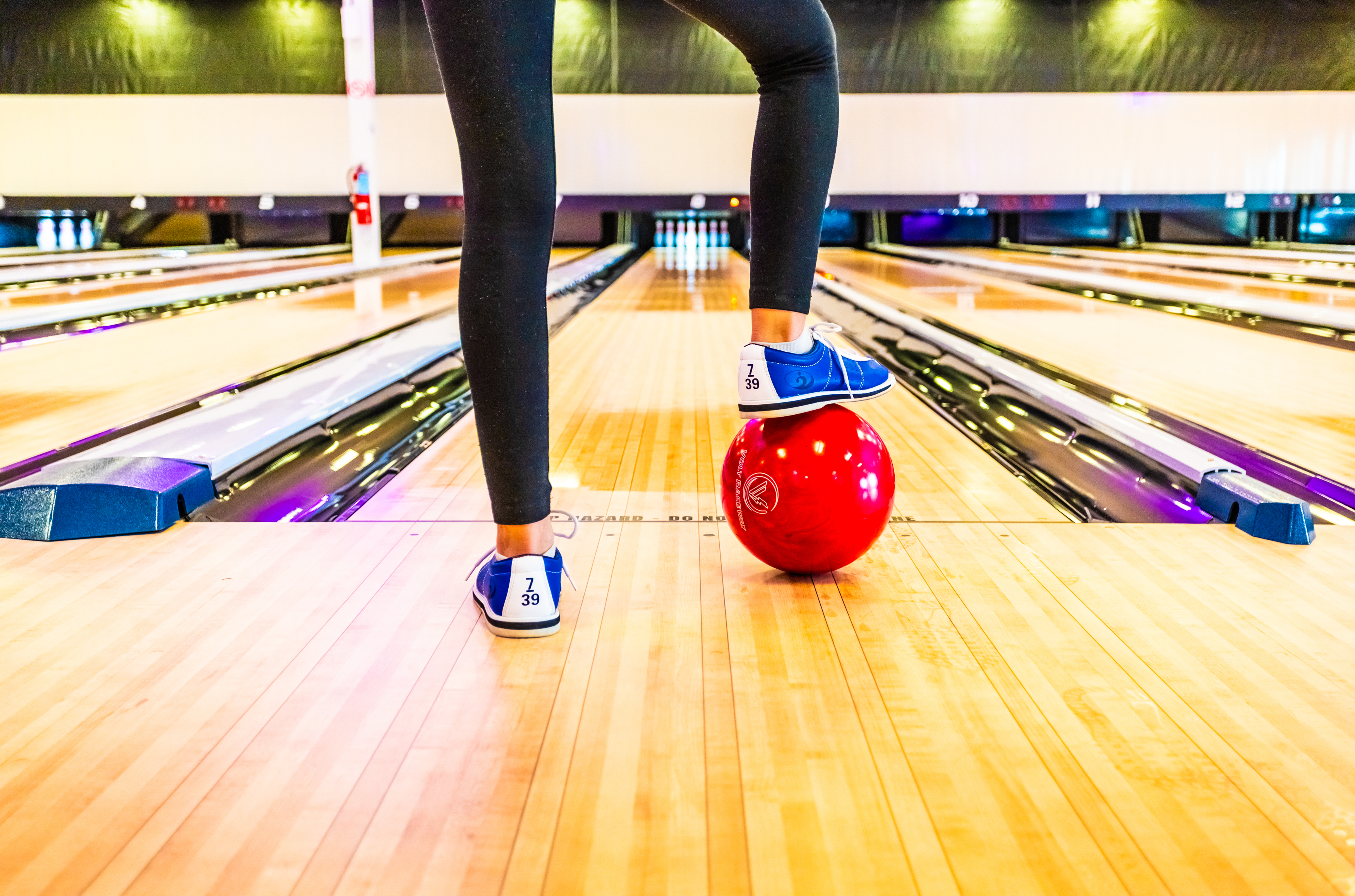 Foot resting on bowling ball in front of lane