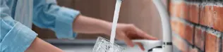 Woman filling a glass of water from the kitchen tap