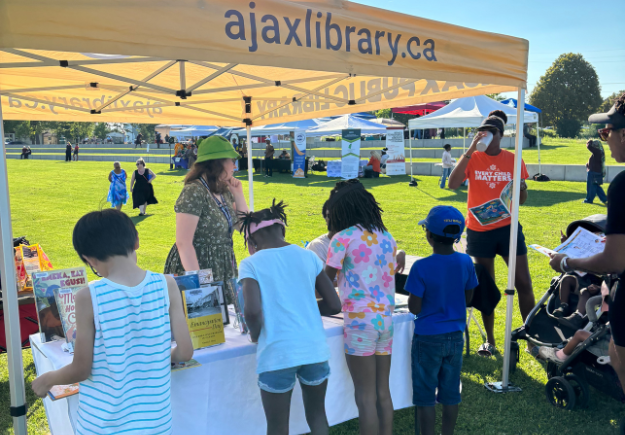 Youth and people gathered around the Ajax library booth.