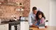 A father helps his daughter with a tablet in the kitchen